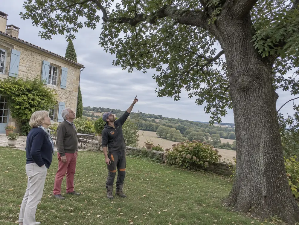 Un artisan montre un chêne à un couple de propriétaires dans leur jardin gersois